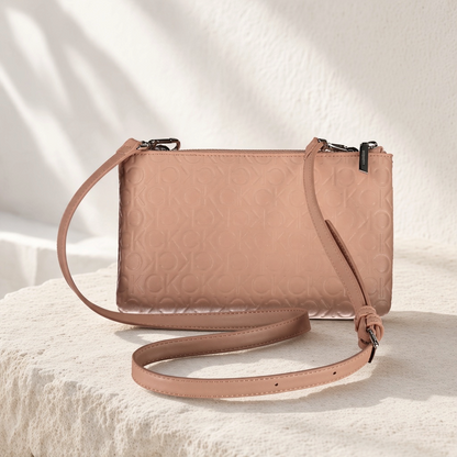 Bolso bandolera liquidationlive Calvin Klein en color rosa con logo grabado, correa ajustable y acabado brillante.