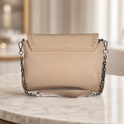 Bolso Byblos de liquidationlive en color beige con solapa de efecto trenzado y cadena plateada sobre mesa de mármol