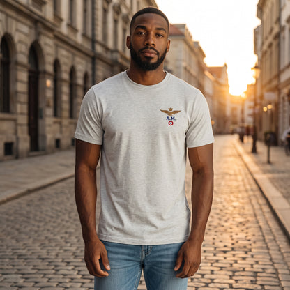 Hombre con camiseta gris de cuello redondo Aeronautica Militare con logo de aviador en una calle empedrada al atardecer