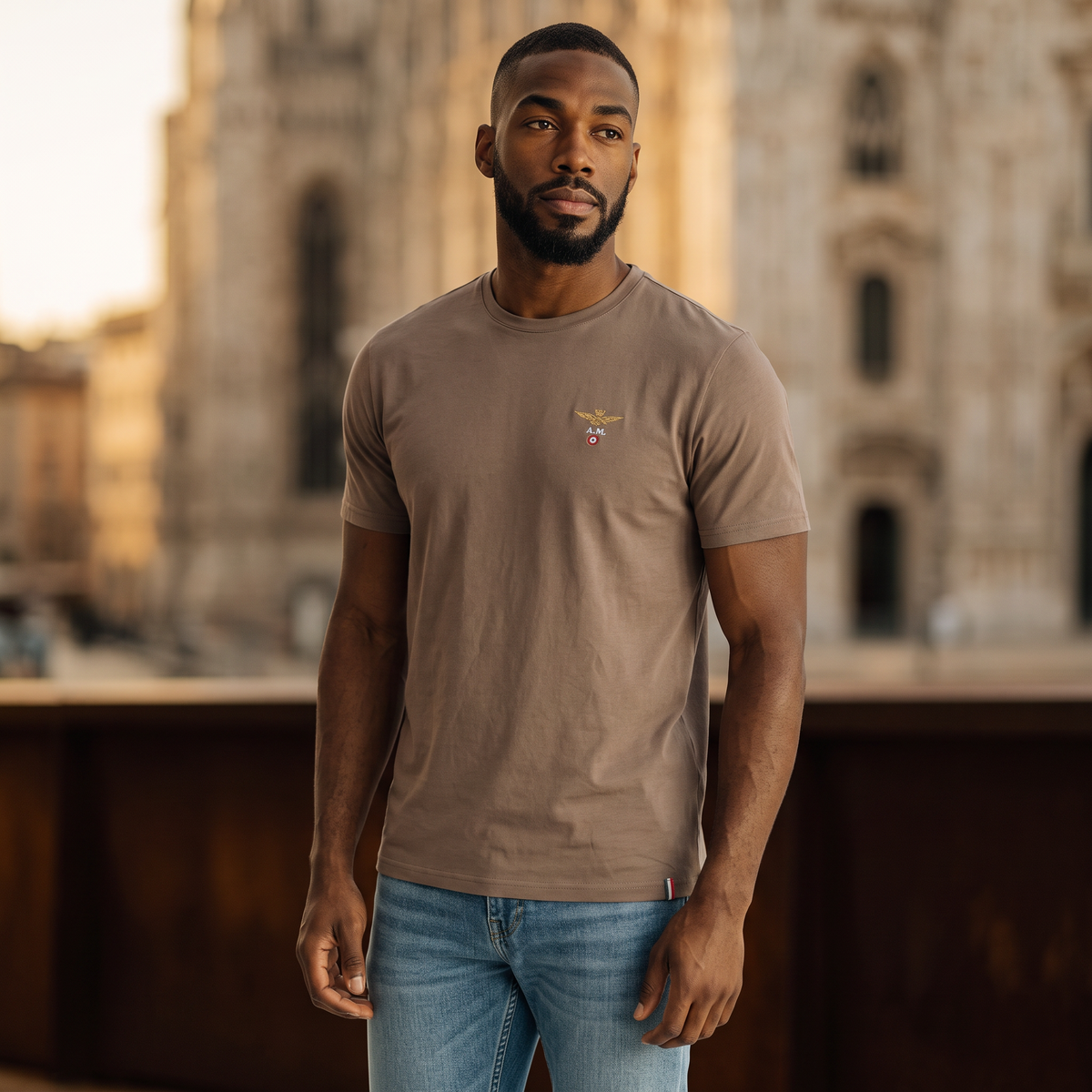Hombre con camiseta marrón de cuello redondo Aeronautica Militare y logo de aviador, estilo casual en exterior