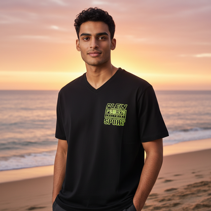 Hombre vistiendo camiseta negra Plein Sport con cuello en V y logo estampado en verde neón en la playa al atardecer