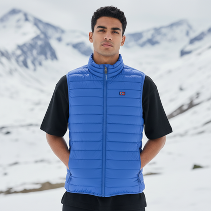 Modelo vistiendo chaleco acolchado azul de liquidationlive con cremallera y logo en paisaje montañoso nevado