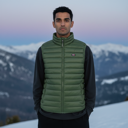 Hombre con chaleco acolchado verde liquidationlive sobre sudadera negra en un paisaje de montaña nevada