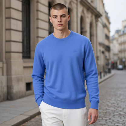 Hombre con jersey azul de cuello redondo La Martina con bordado discreto, combinado con pantalones blancos en la calle