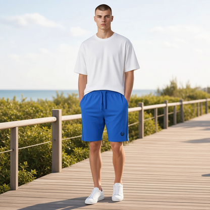 Modelo con pantalón corto azul liquidationlive, camiseta blanca y zapatillas en un paseo de madera junto al mar.