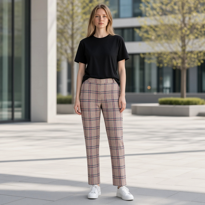 Modelo vistiendo pantalón de cuadros Gant en tonos beige y marrón con camiseta negra y zapatillas blancas en exterior