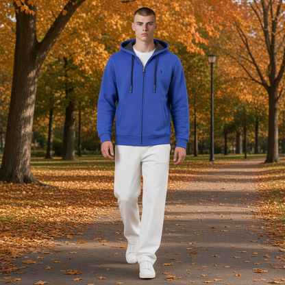 Hombre caminando en parque otoñal vistiendo sudadera azul con cremallera y capucha de la marca liquidationlive