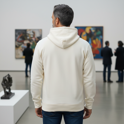 Hombre de espaldas vistiendo sudadera con capucha color crema de liquidationlive en una galería de arte