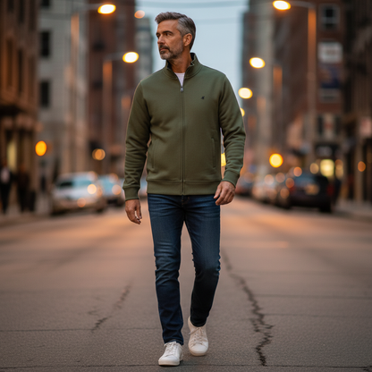 Hombre caminando por la calle con sudadera verde con cremallera U.S. Grand, vaqueros y zapatillas blancas