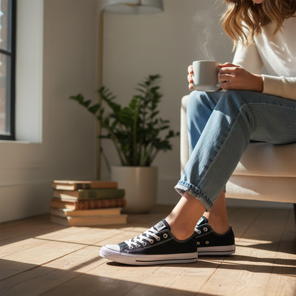 Zapatillas Converse negras con suela blanca en contraste, usadas por una mujer con vaqueros en un salón luminoso.